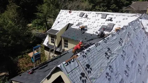 Workers installing new slate roof on house.