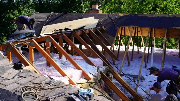 Roofers repairing attic structure with insulation visible.