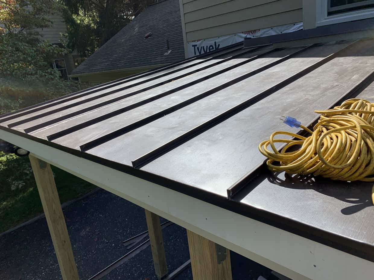 Metal roof installation with yellow extension cord.